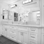 חדר אמבטיה לבן עם רצפת אריחים אפורה ומשטח עבודה לבן גרניט