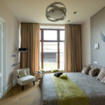 עיצוב חדר שינה עם חלון פנורמי וציור קיר מעל המיטה
