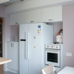 Ledusskapis virtuves interjerā zem sienas skapjiem