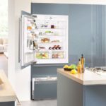 Lednice v interiéru kuchyně zabudovaná do šedé skříně