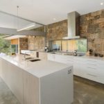 Virtuvės siena iš dekoratyvinio akmens atsiveria į terasą