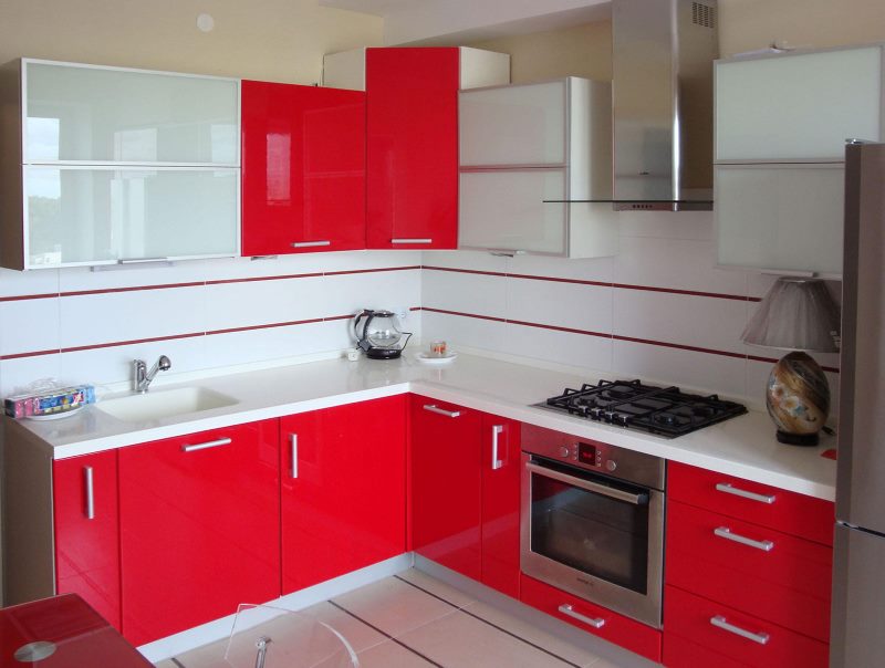 Muebles rojos y blancos en una pequeña cocina.