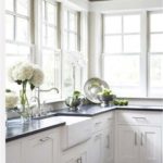 Virtuves mēbeles gaišas virtuves stūrī ar lieliem logiem