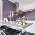 Le papier peint luxueux en relief violet est devenu une décoration et un accent de la cuisine avec un système d'armoires blanc neige