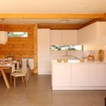 Cocina blanca estricta en la casa con molduras de madera