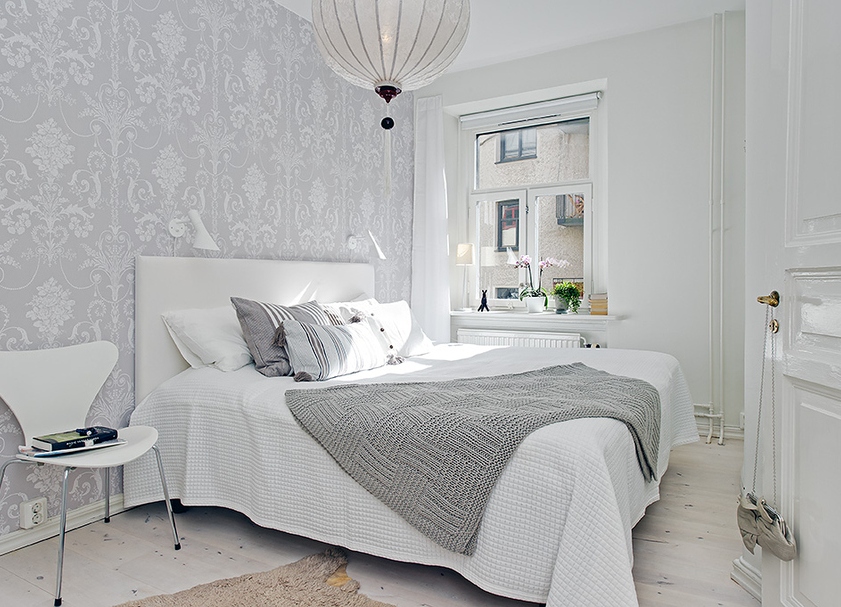 Interiorul unui dormitor mic, în culori gri și alb