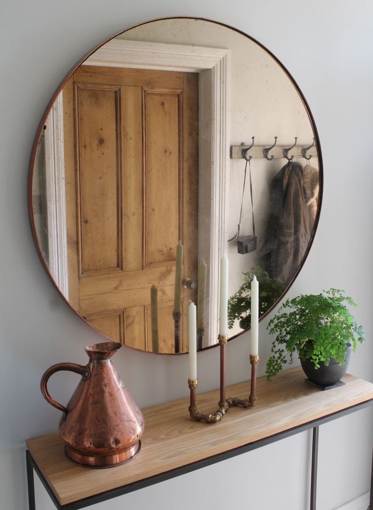 مرآة مستديرة بإطار رفيع مقابل باب خشبي