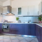 Kampinė virtuvė su purpurinėmis naktinėmis lentomis.