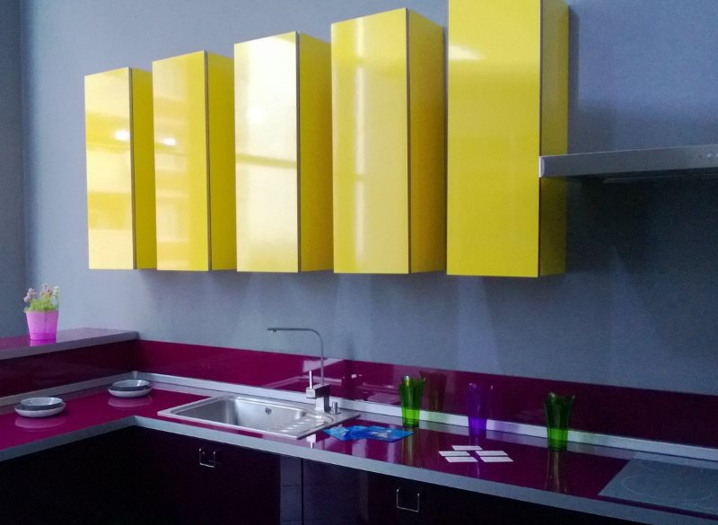 Žluté závěsné skříňky v kuchyni s fialovými deskami