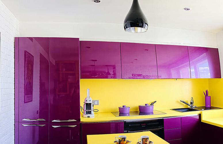 Dzeltens priekšauts virtuves interjerā ar purpursarkanām mēbelēm