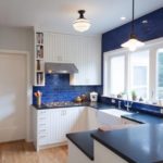 Balta virtuve ar zilu ķieģeļu darba zonu un zilu darba virsmu