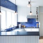 Baltas virtuves mēbeles ar zilām flīzēm.