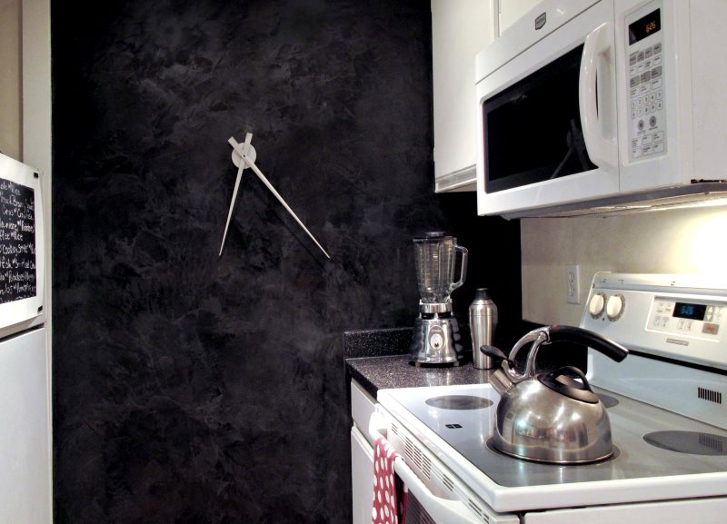 Rellotge de disseny a la paret fosca d’una petita cuina