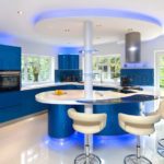 Stort køkken med blå møbler og en elegant ø med en morgenmadsbar