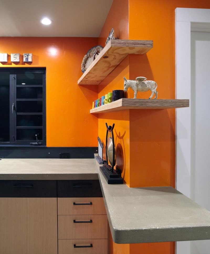 Ξύλινα ράφια σε έναν πορτοκαλί τοίχο κουζίνας