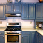 Tumši zilas klasiskas mēbeles gaišā virtuvē