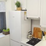 Réfrigérateur blanc près de la fenêtre dans une petite cuisine