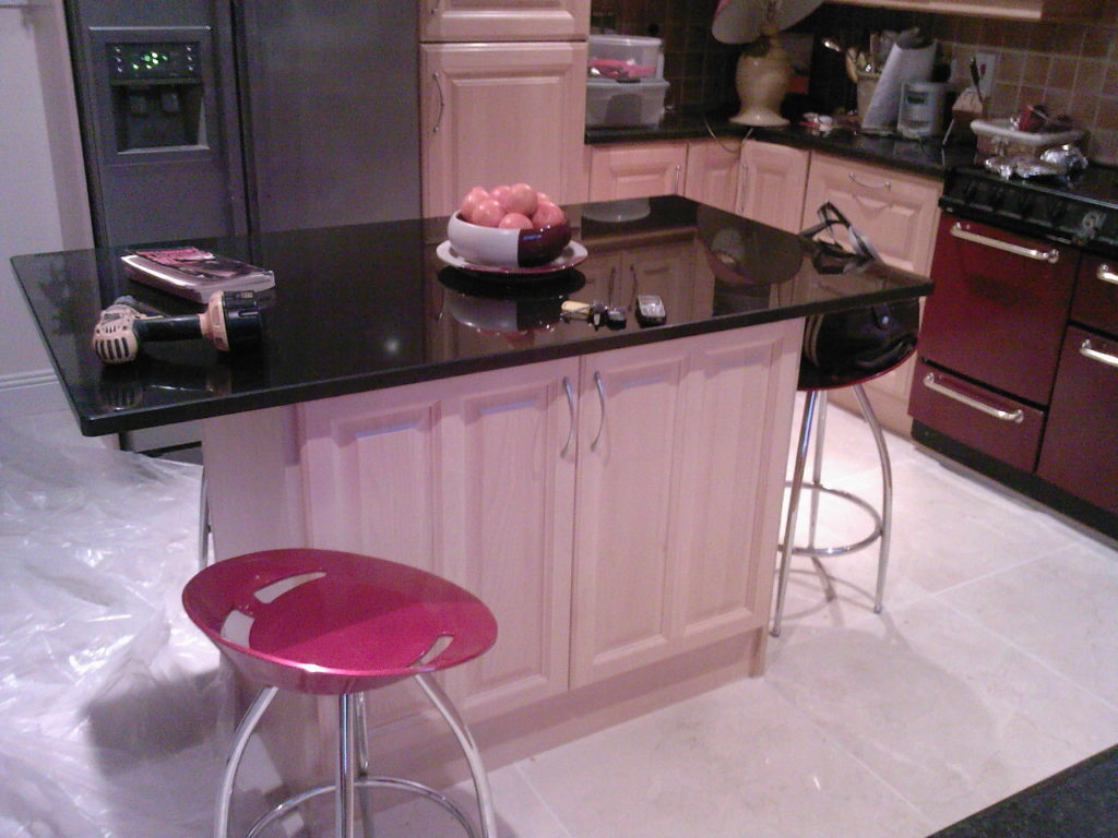 Black countertop kitchen island with pink doors