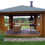 Metal barbecue in the gazebo with wooden floor.