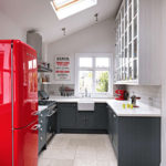 Raudonas šaldytuvas privataus namo virtuvėje