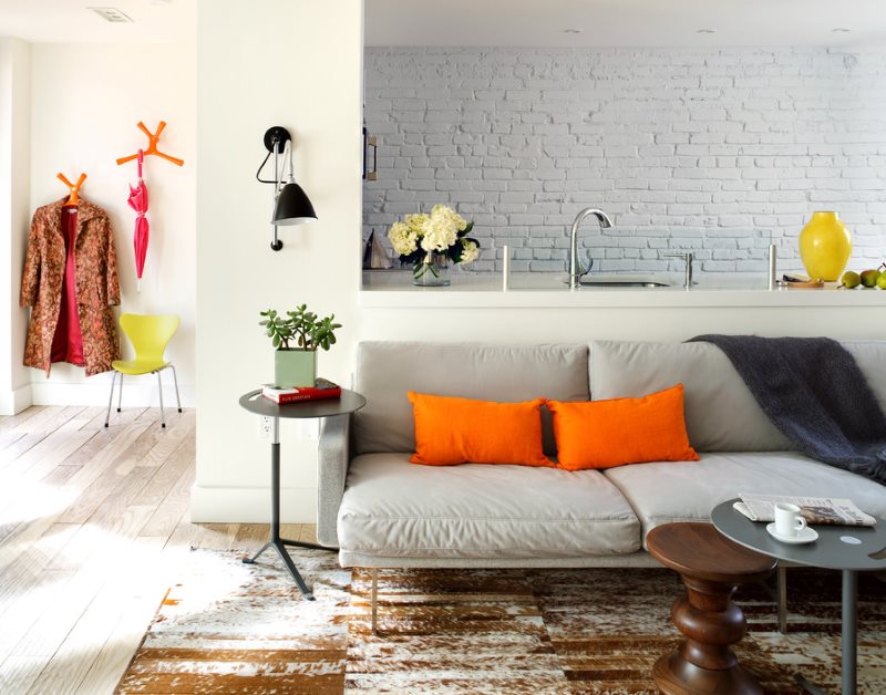 Oranžové polštáře na šedé pohovce v obývacím pokoji v kuchyni