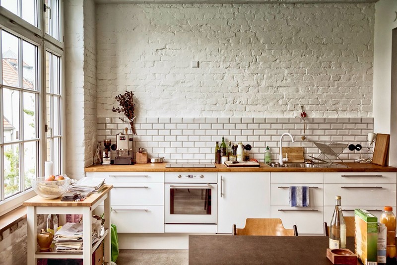 Balti krāsota siena industriālā stila virtuvē