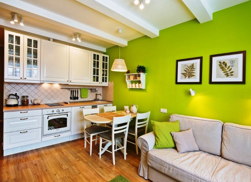 Green wall in the kitchen-living room with a white set