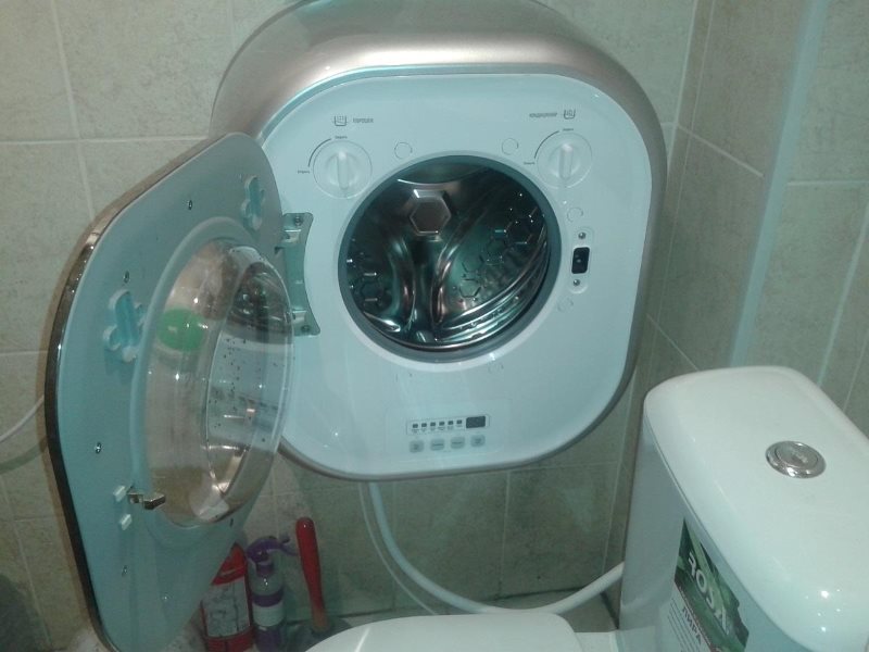 Kompakta veļas mašīna pie sienas vannas istabā