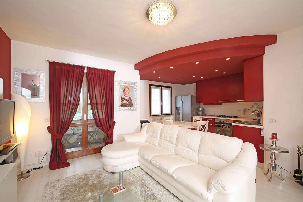 Sofa trắng trong phòng khách nhà bếp với rèm cửa màu đỏ tía