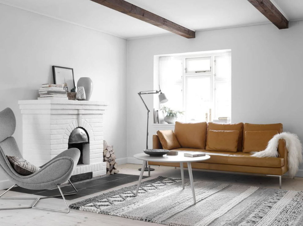 Sofá de couro em uma sala de estar branca com lareira