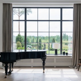 Um piano preto na frente de uma grande janela
