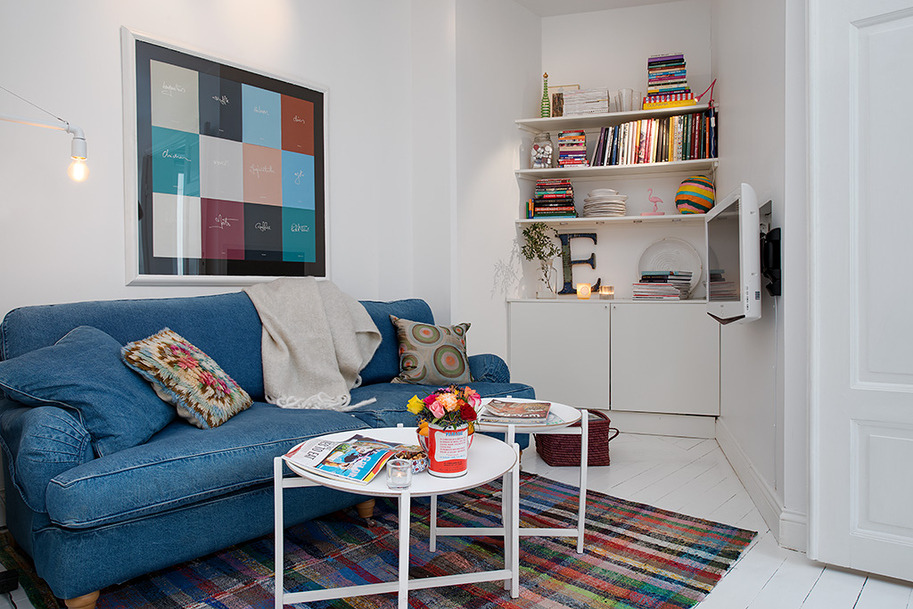 أريكة زرقاء في غرفة معيشة صغيرة على الطراز الاسكندنافي