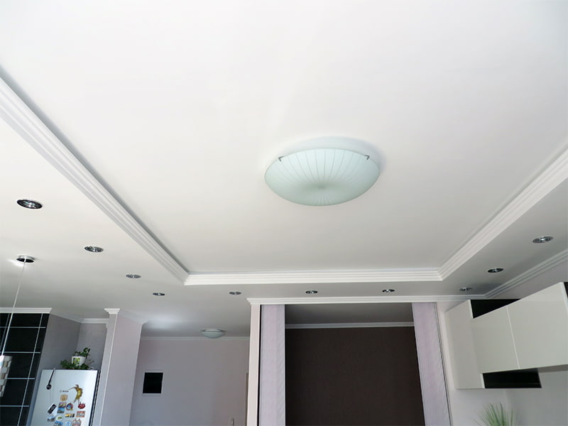 Overhead lamp on a two-level ceiling made of gypsum plasterboard