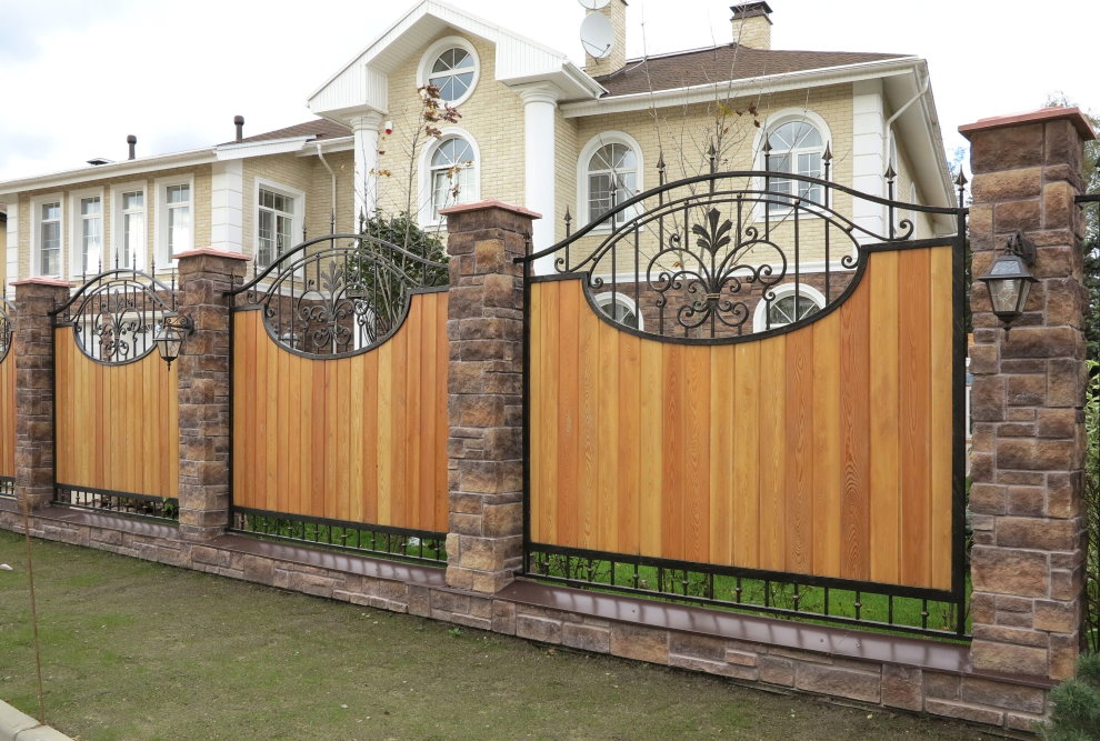 Wooden fence with forged elements on stone pillars