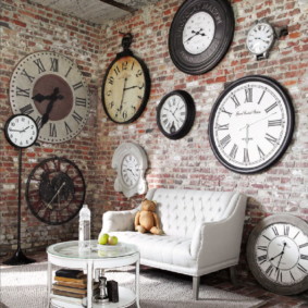 Vintažinių laikrodžių kolekcija ant plytų sienos