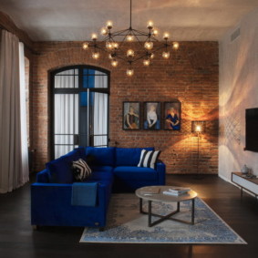 Kronleuchter über einem blauen eckigen Sofa