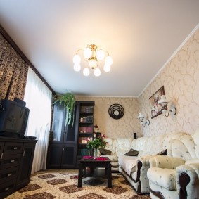 Ryškus apšvietimas gyvenamajame kambaryje su baltomis lubomis