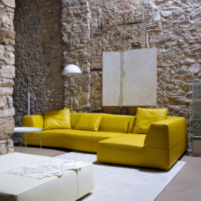 Bright sofa against the background of stone walls