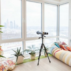 Télescope domestique près d'une fenêtre panoramique