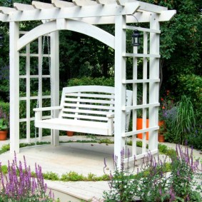White pergola with a wooden swing