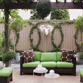 Dārza dīvāns ar zaļiem spilveniem