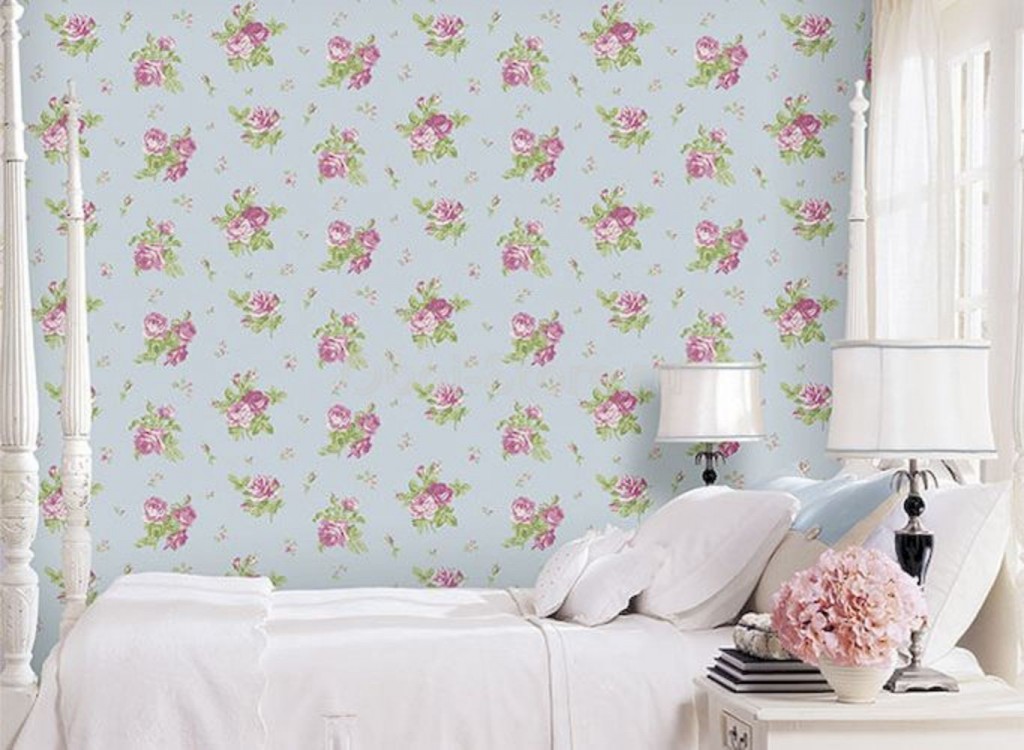 Small flowers on the wallpaper behind the girl’s bed