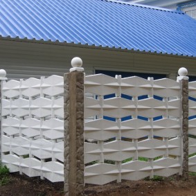 Vita bollar på pelarna i ett konkret staket
