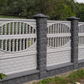Bijeli betonski dijelovi ograde na sivim stupovima