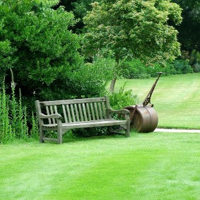 Дрвена клупа на плацу са вртом и травњаком
