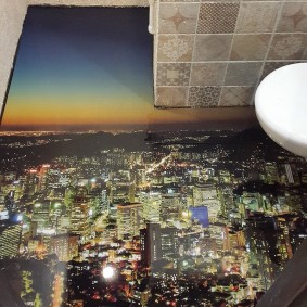 Piso con la imagen de la ciudad de noche en el baño de la casa de paneles
