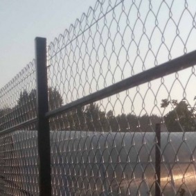Polikarbonát üvegház egy háló kerítés mögött