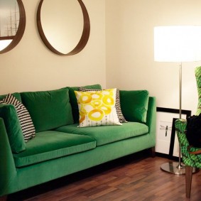 Decoración de pared de espejo sobre un sofá verde