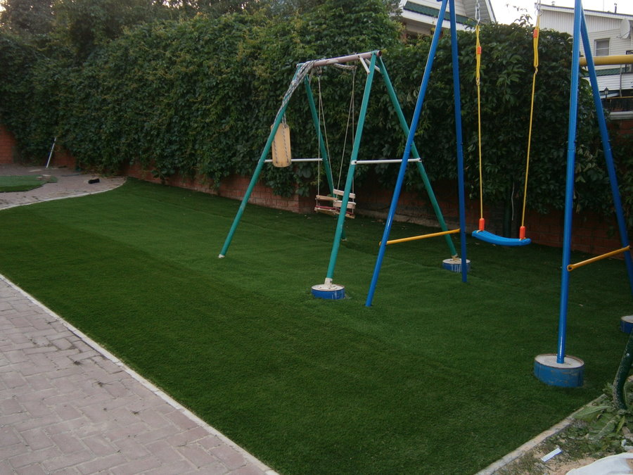 Children's swing on the playground with a sports-type lawn