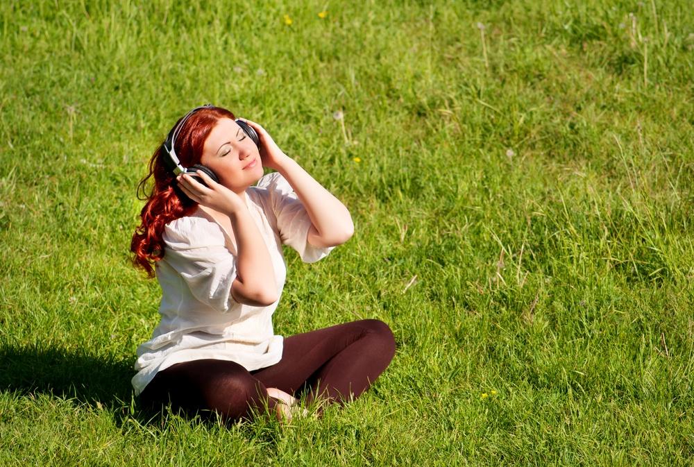 Mergaitė ausinėse ant pievos vejos